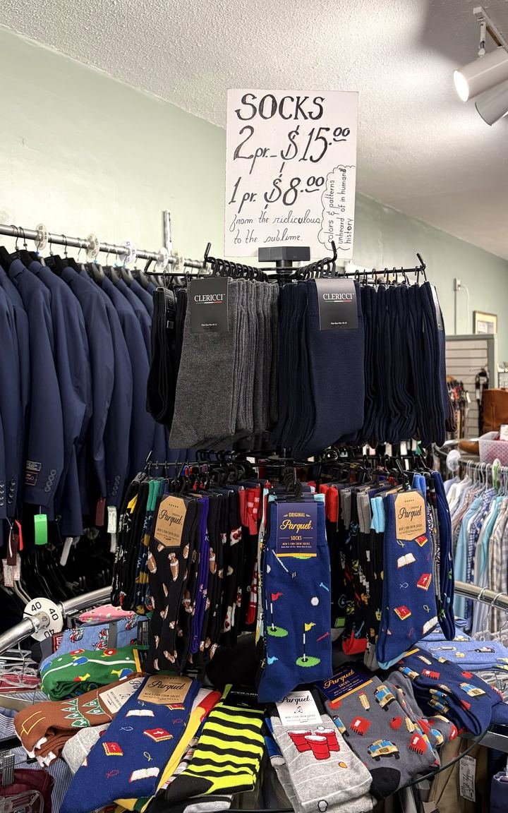 The sock rack under the store's own hand-written sign — plain dress socks above, novelty patterns below.